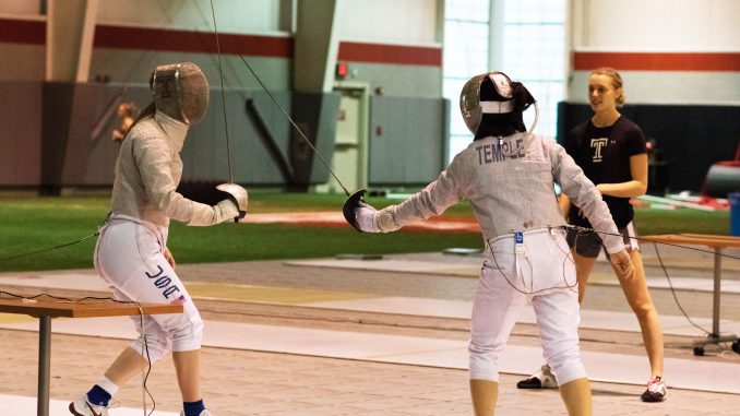 Sophomore sabre Kerry Plunkett (background) watches while sophomore sabre Malia Hee (right) and freshman sabre Eva Hinds fence during practice on Friday in the Student Pavilion. | JAMIE COTTRELL / THE TEMPLE NEWS