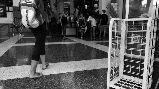 Students walk by an empty bin previously reserved for the New York Times. Residential Life and Student Activities canceled the readership program. ( KATE MCCANN / TTN )