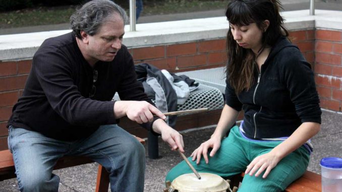 Dan Gorlin teaches a student how to play drum on Oct. 14. Gorlin is the founder of Alokli African Dance, a drum circle that meets Sundays on Main Campus. ( SABA AREGAI // TTN )