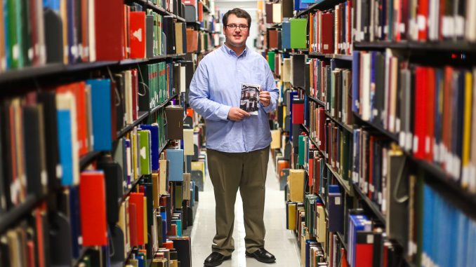 Freshman journalism major Max Buchdahl stands in Paley library while holding his self-published book, “Return of the Exiled.” Andrew Thayer | TTN