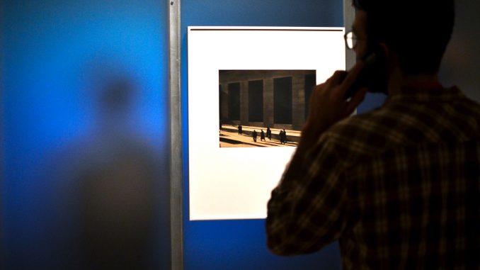 A man views Paul Strand’s photograph, “Wall Street, New York” while other patrons watch Strand’s first film, “Manhatta.” Jenny Kerrigan |TTN