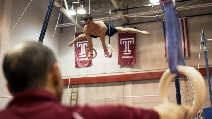 Longtime men’s gymnastics coach Fred Turoff watches sophomore Casey Polizzotto practice on the rings in McGonigle Hall on Monday. | Kara Milstein TTN