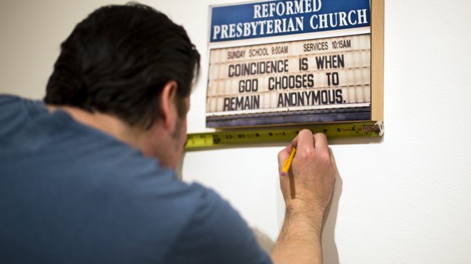 Brian Murray hangs a piece for the current exhibit at the Gershman Y. | Kara Milstein TTN