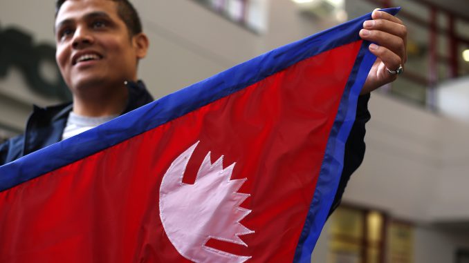 Buddha Khatri, who is pursuing a doctorate in chemistry, holds a Nepal flag at the Student Center on Friday. Geometric instructions on reproducing a Nepali flag are part of the country's constitution, making it "the most mathematical flag," he said. | JENNY KERRIGAN TTN