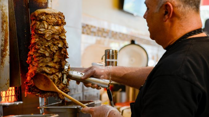 Co-owner, Omar Alsaadi, carves layers of chicken shawarma for the lunch rush. | Brianna Spause TTN