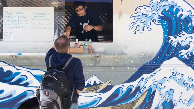 Jeff Ji, owner of the Tabeteki and Vegan Tree food trucks, serves lunch to a student. | Margo Reed TTN