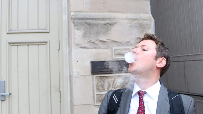 John Basenfelder, a third-year law student, is one of many Temple students who have taken up vaping. Vaping is the common term for using an e-cigarette or vaporizer that heats liquid, which contains nicotine, to produce vapor the user inhales. The practice has been adopted by many former smokers as a healthier alternative to smoking, but some are still skeptical about its benefits. | Evan Easterling TTN