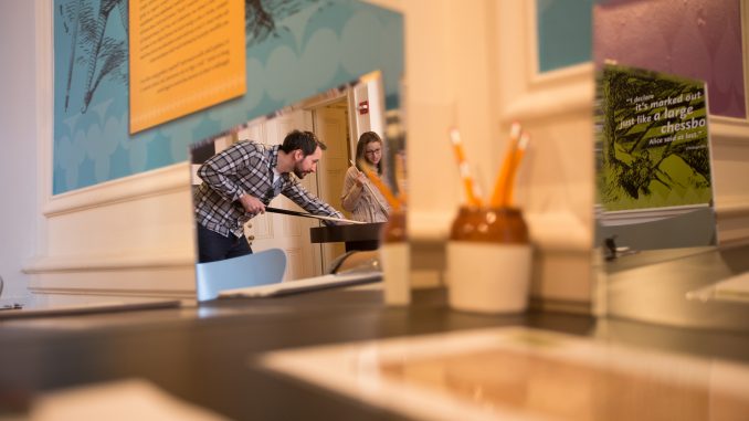 Jeff Kinslow (left), and Allison Cahill play a game of circular billiards at the “Alice in Wonderland” 150th anniversary exhibit at the Rosenbach Museum. | Margo Reed TTN